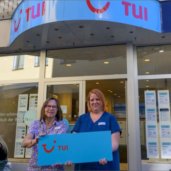 TUI Deutschland GmbH: Zwei Mitarbeiterinnen stehen vor Ihrem Laden im Kohlenkamp und halten ein blaues TUI Schild mit roter Schrift in der Hand | Foto: Walter Schernstein