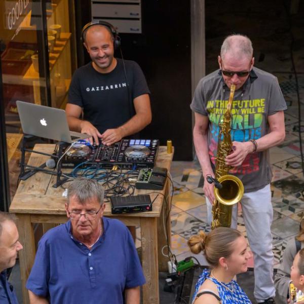 Ein DJ und ein Saxofonist musizieren zusammen. Im Vordergrund sind zwei Gäste zu sehen | Foto: Walter Schernstein