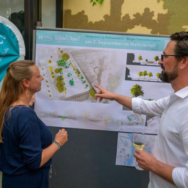 Einige Bürger*innen schauen sich die Planung des Rathausmarktplatzes auf einem Plakat an und lassen sich den Entwurf erläutern. | Foto: Walter Schernstein