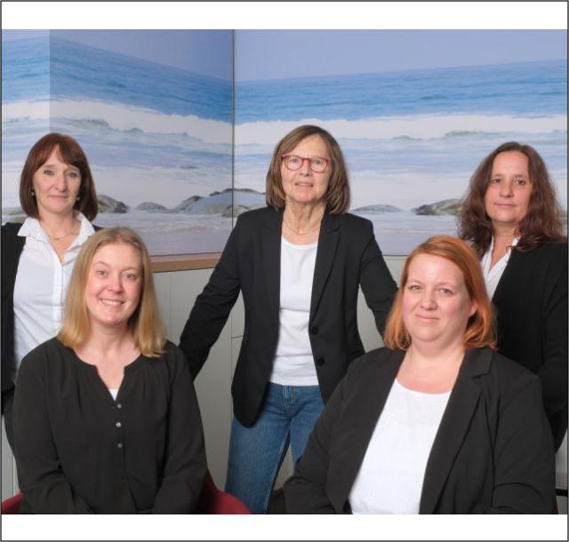 Das Team des TUI-Reisebüros posiert für das Foto vor einer Fototapete | Foto: TUI